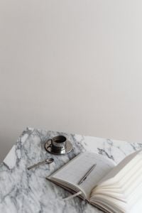 Kaboompics - Overhead Chrome Coffee Cup and Spoon beside Open Planner on Marble, Wide Desk Still Life
