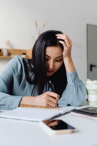 Kaboompics - Frustrated Asian Woman Writing Notes at Her Desk