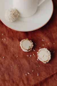 Kaboompics - Coconut Truffle Cross-Sections beside a White Cup on Rust Linen, Homemade Candy Still Life