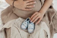 Kaboompics - Close-Up Pregnant Belly and Blue Baby Shoes with Neutral Baby Clothes