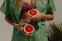 Kaboompics - Woman in Green Beach Cover-Up Holding Grapefruit Halves