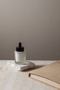 Kaboompics - Skincare Serum Bottle Mockup on Travertine beside an Open Book