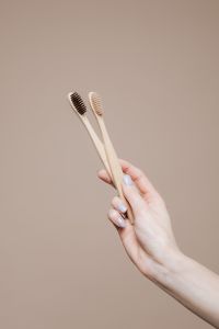Kaboompics - Two Bamboo Toothbrushes Held Against Beige Background, Sustainable Oral Care Product Photo