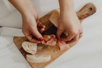 Kaboompics - Hands Preparing Bread and Prosciutto on a Wooden Board