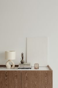 Kaboompics - Minimalist Home Decor with Lamp, Books and Glass Votive on a Neutral Sideboard