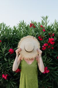 Kaboompics - Woman Hiding Her Face with a Straw Hat Among Pink Flowers