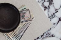Kaboompics - Dollar Bills Fanned Beside a Black Bowl on Beige Linen