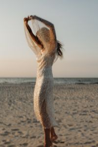 Kaboompics - Woman Raising Arms in Sequin Dress by the Sea