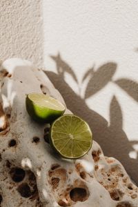 Kaboompics - Lime Halves on Textured Coral Rock with Leaf Shadow