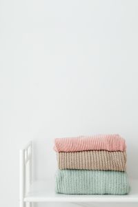 Kaboompics - Stack of Pastel Sweaters on a White Shelf