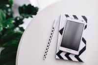 Kaboompics - White Smartphone and Geometric Notebook with Patterned Pencil on a Curved Table beside Greenery