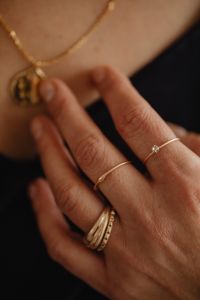Kaboompics - Ringed Hand Touching Gold Pendant Necklace Against Black Clothing, Fashion Jewelry Detail