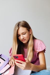 Kaboompics - Young Woman Checking Phone beside School Supplies