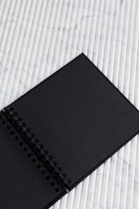 Kaboompics - Black Spiral Notebook on White Marble with Diagonal Lines and Copy Space