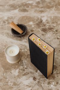 Kaboompics - Black Book Decorated with Daisies beside Candle and Bowl