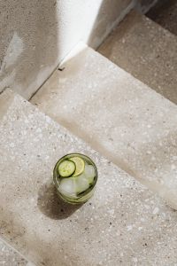 Kaboompics - Overhead Cucumber and Lime Detox Water with Ice on Textured Concrete Steps, Summer Drink Flat Lay