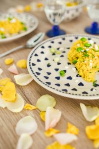 Kaboompics - Yellow rice with greens on a cute plate with blue hearts and a table decorated with flower petals