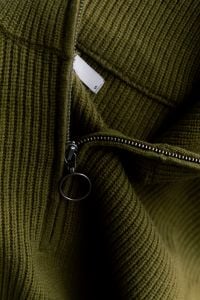Kaboompics - Olive Green Zip Sweater on an Acrylic Chair for Minimalist Fashion