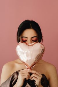Kaboompics - Woman Hiding Behind Rose Gold Heart Balloon