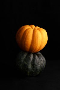 Kaboompics - Orange and Dark Green Pumpkin Stacked on Black Background