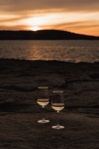 Kaboompics - Two Wine Glasses Against the Sunset on a Rocky Coast