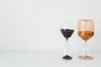 Kaboompics - Black and Amber Glass Hourglasses on a White Table with Open Left Copy Space