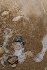 Kaboompics - Foamy Shoreline Washing Over Pebbles On Sandy Beach