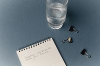 Kaboompics - Minimal Desk Flat Lay With Notebook Glass And Binder Clips