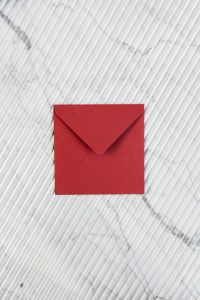Kaboompics - Red Envelope with Generous Copy Space on White Marble, Vertical Stationery Background