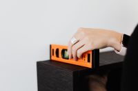 Kaboompics - Hand Checking an Orange Spirit Level on a Dark Wooden Surface during Home Renovation