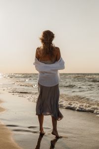 Kaboompics - Faceless Woman Standing at Waterline in White Shirt and Satin Skirt