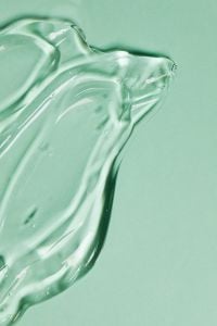 Kaboompics - Glossy Skincare Transparent Gel Macro Texture with Light Reflections on Green Background