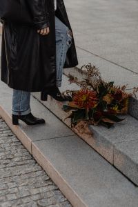 Kaboompics - Woman in Black Coat Standing Beside an Autumn Bouquet on Steps