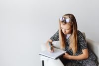 Kaboompics - Schoolgirl Writing Homework in an Armchair with Copy Space