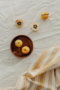 Kaboompics - Overhead Dish of Whole and Halved Japanese Quince with Striped Towel, Fruit Still Life