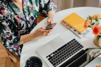 Kaboompics - Woman Using a Smartphone at a Laptop Workspace with Blueberries