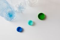 Kaboompics - Clear Plastic Bottles and Loose Caps Scattered on White