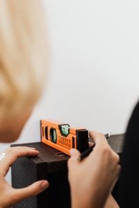 Kaboompics - Woman Checking a Spirit Level on a Dark Wooden Shelf during a Home DIY Project