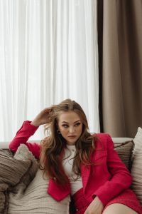 Kaboompics - Woman Sitting on a Sofa in a Fuchsia Skirt Suit