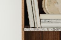 Kaboompics - Book Spines and Round Marble Trays on a Walnut Bookshelf