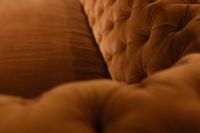 Kaboompics - Orange Velvet Sofa Side with Deep Tufting and Blurred Foreground Cushion