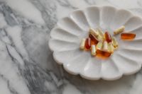 Kaboompics - Vitamins and Capsules on a White Scalloped Plate