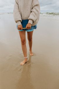 Kaboompics - Barefoot Woman Walking Along the Shore with a Blue Book in Her Hands, Beach Reading Lifestyle