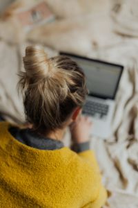 Kaboompics - Overhead Laptop Work from Bed with Woman's Hair Bun and Soft White Bedding
