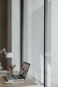Kaboompics - Vertical Detail of White Desk Lamp and Pencil Holder above a Laptop by the Window