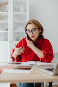Kaboompics - Close-Up of Woman Taking Notes while Holding Phone between Ear and Shoulder at Her Desk