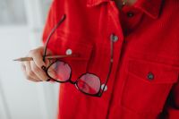 Kaboompics - Eyeglasses and Pencil in Woman's Hand against Red Blouse, Creative Workspace Detail