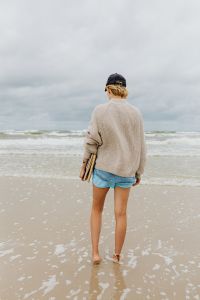 Kaboompics - Woman in a Knit Sweater and Denim Shorts Walking into the Baltic Sea with Books