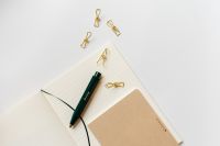 Kaboompics - Dark Green Fountain Pen on Open Lined Notebook with Gold Clips and Beige Notepad, Wide Office Flat Lay