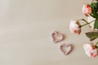 Kaboompics - Pink Roses and Two Beaded Hearts on Beige Copy Space